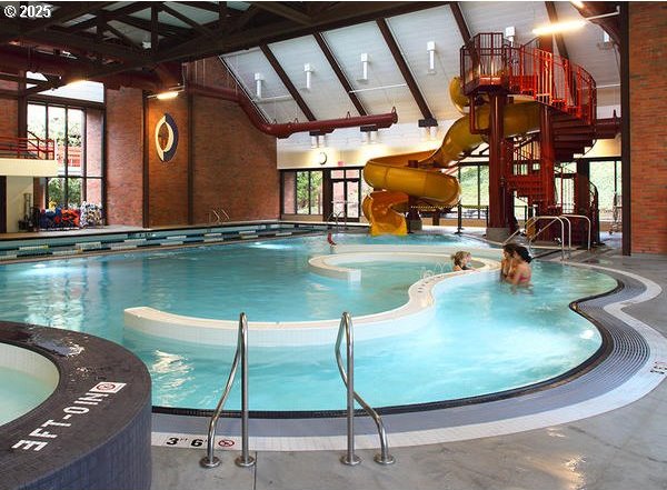 view of swimming pool with a water slide and a hot tub