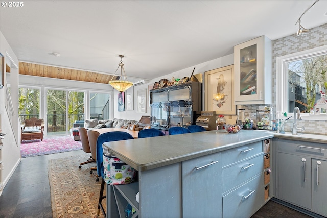 kitchen featuring sink, gray cabinetry, tasteful backsplash, decorative light fixtures, and kitchen peninsula