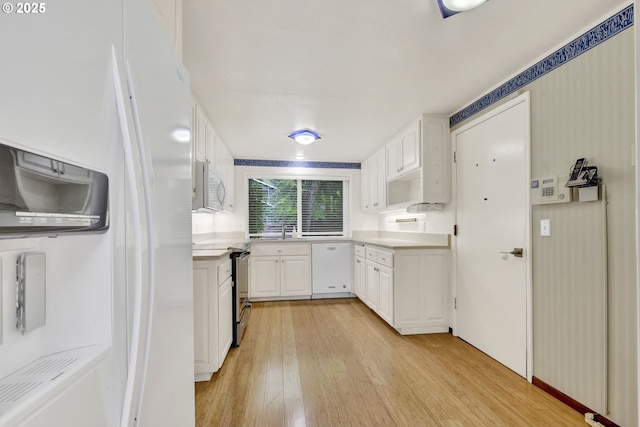 kitchen featuring white appliances, light wood-style floors, white cabinets, and light countertops