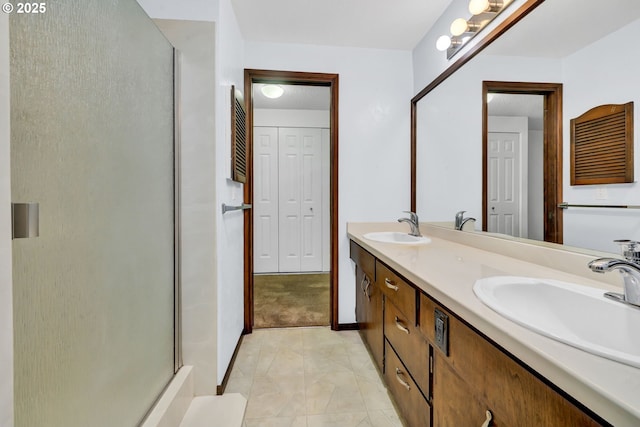 full bathroom with a shower with door, double vanity, and baseboards