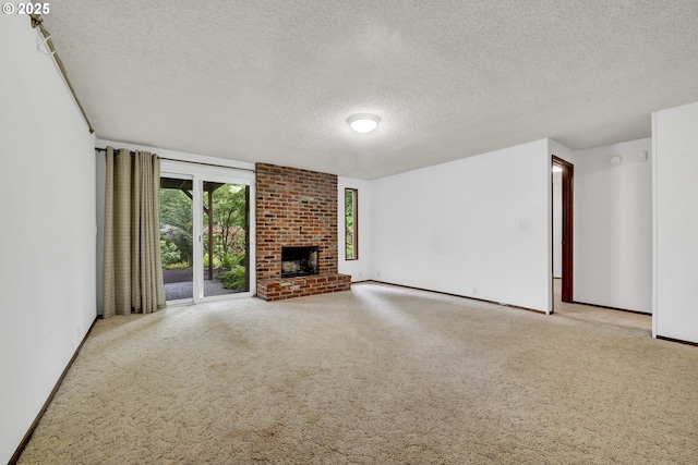 unfurnished living room with a textured ceiling, carpet floors, a brick fireplace, and baseboards