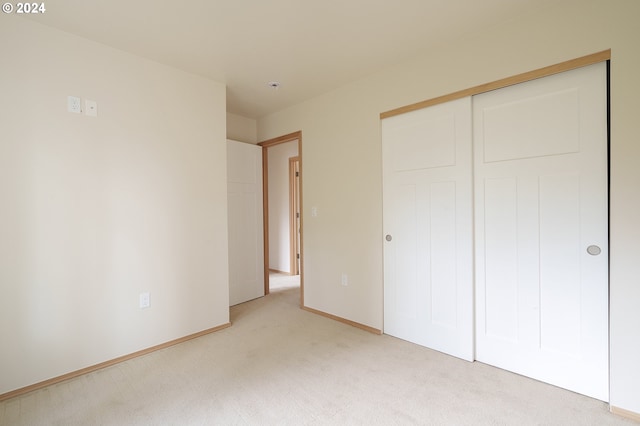 unfurnished bedroom with a closet and light carpet