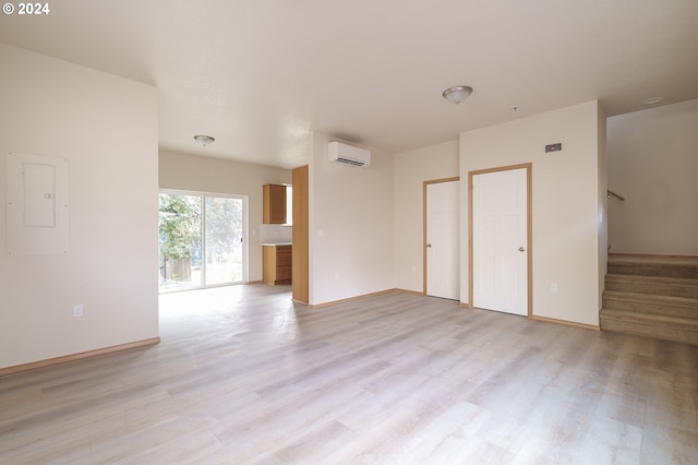 unfurnished room with a wall mounted AC, electric panel, and light wood-type flooring