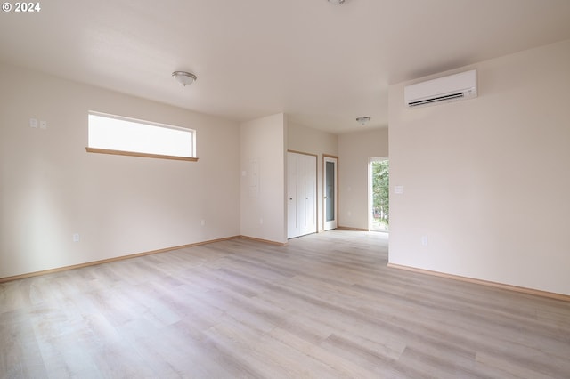 spare room featuring a wall mounted air conditioner and light hardwood / wood-style floors