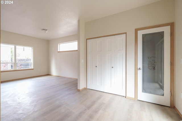 unfurnished bedroom featuring a textured ceiling, a closet, and light wood-type flooring