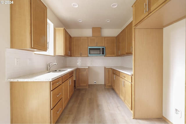 kitchen with tasteful backsplash, sink, and light wood-type flooring