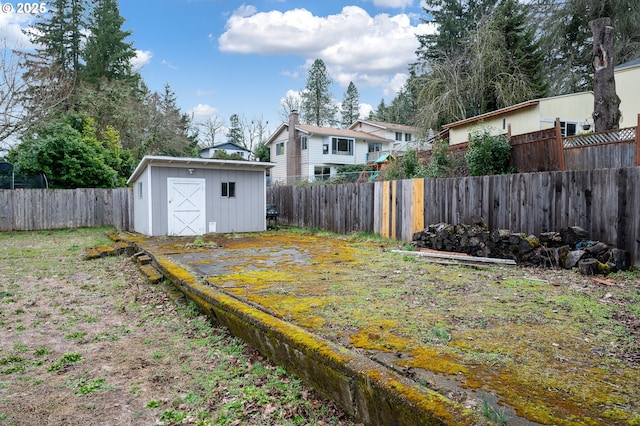 view of yard featuring an outbuilding, a fenced backyard, and a storage unit