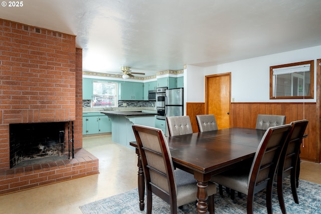 dining room featuring a wainscoted wall, a fireplace, and a ceiling fan