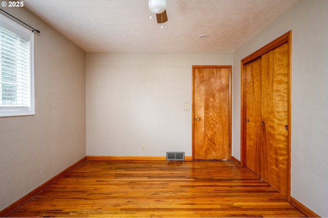 empty room with ceiling fan, light wood-style flooring, visible vents, and baseboards