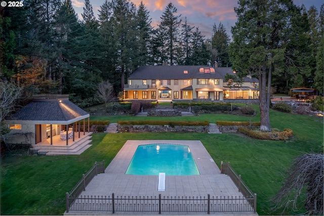 rear view of property featuring a yard, fence private yard, and an outdoor pool