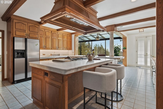 kitchen with light tile patterned floors, a kitchen island, custom exhaust hood, stainless steel appliances, and light countertops