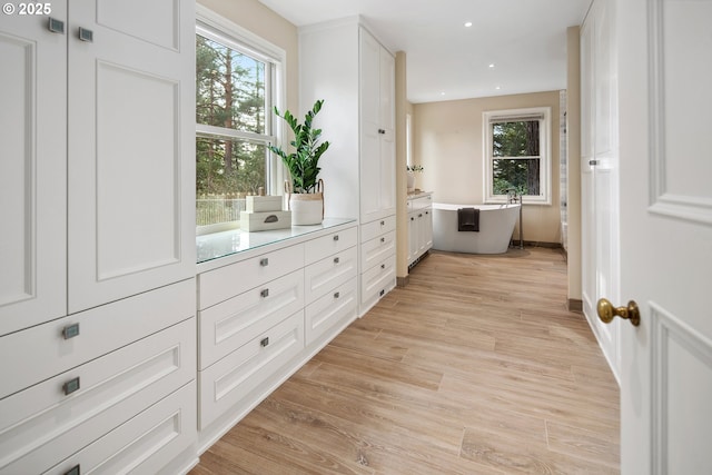 hallway with light wood finished floors, recessed lighting, and baseboards