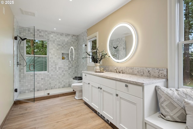 full bath featuring a shower stall, toilet, vanity, and wood finished floors