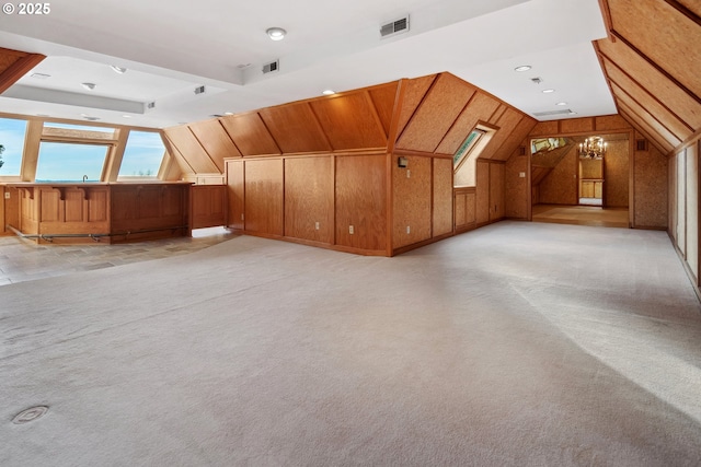 bonus room featuring visible vents, lofted ceiling, light colored carpet, and wood walls