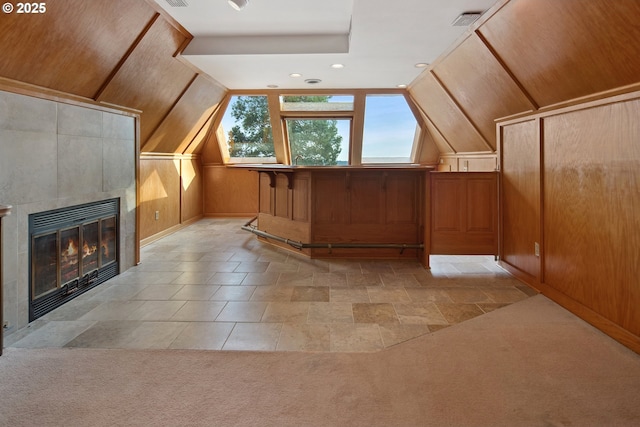 additional living space featuring visible vents, lofted ceiling, light carpet, and a tile fireplace