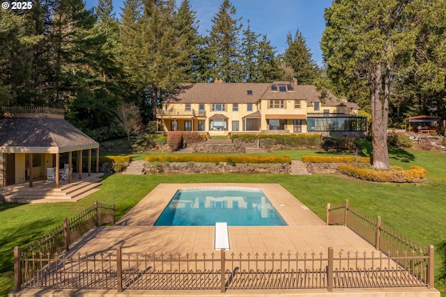 pool featuring fence, a lawn, and a diving board