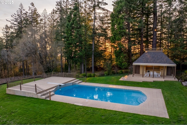 view of swimming pool with fence, a yard, an outdoor structure, a fenced in pool, and a patio area