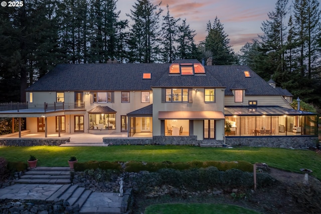 rear view of property featuring a patio, a yard, and a chimney