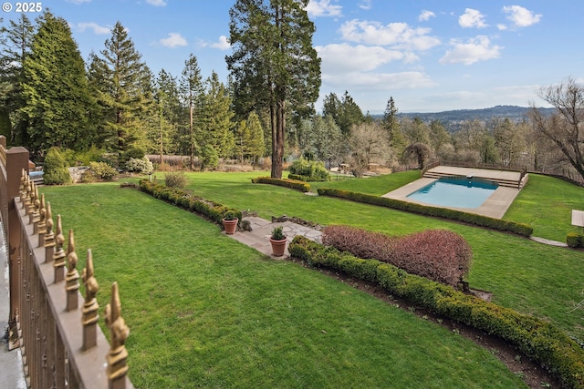 view of yard with a patio area, an outdoor pool, and a forest view