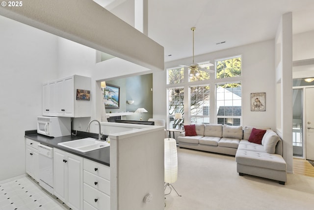 kitchen with sink, white appliances, kitchen peninsula, and white cabinets