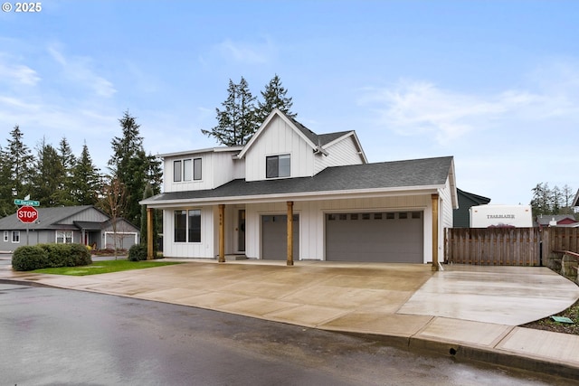 modern farmhouse with concrete driveway, board and batten siding, fence, and roof with shingles