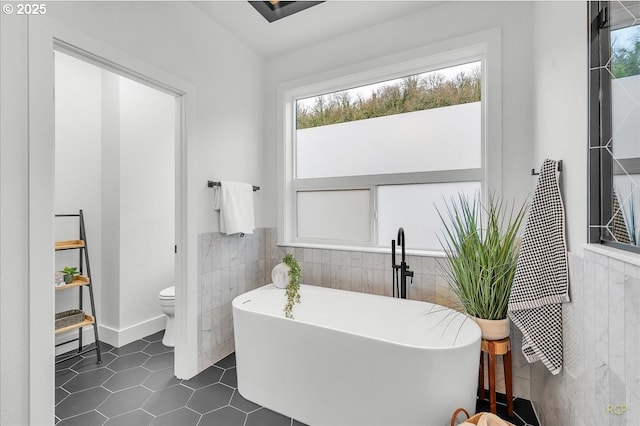 bathroom featuring tile patterned floors, toilet, and a bathing tub