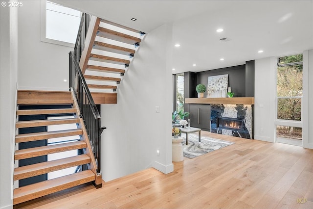 stairway with a fireplace and hardwood / wood-style floors