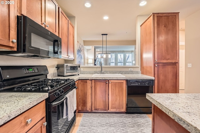 kitchen with pendant lighting, light stone countertops, sink, and black appliances