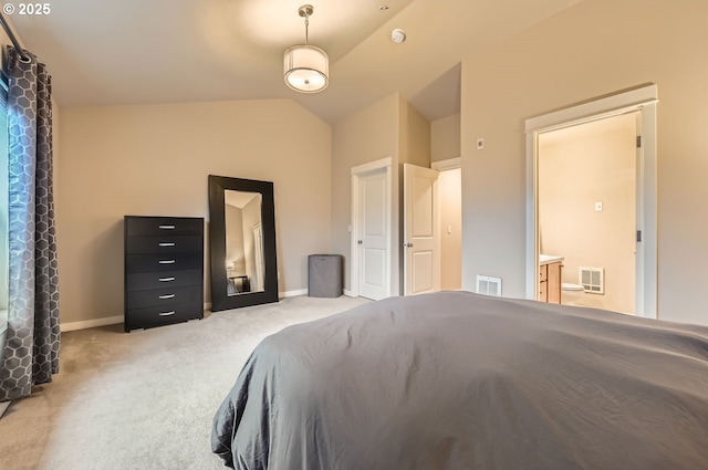 bedroom with light colored carpet, lofted ceiling, and ensuite bath