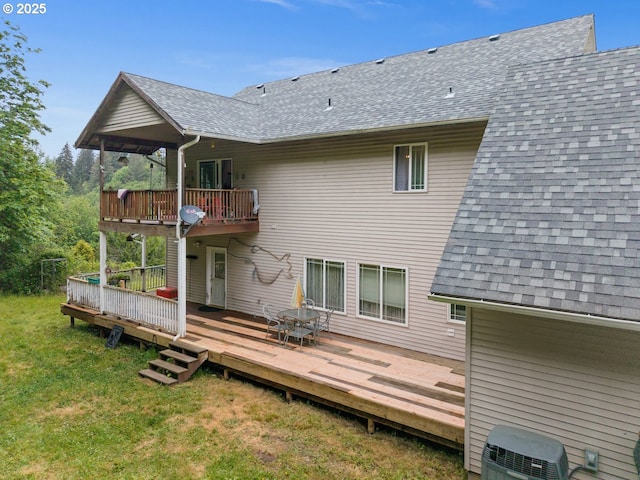 back of house featuring roof with shingles, a lawn, and a balcony