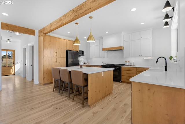 25053 Larson Rd, Monroe, OR 97456 - kitchen featuring black gas range, freestanding refrigerator, light wood finished floors, a breakfast bar area, and premium range hood