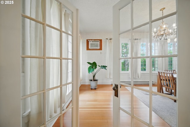 113 NE 7th Ave, Milton-Freewater, OR 97862 - hall featuring a wall mounted air conditioner, wood finished floors, a chandelier, and a baseboard radiator