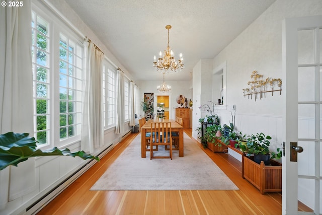 113 NE 7th Ave, Milton-Freewater, OR 97862 - dining room featuring a chandelier, healthy amount of natural light, wood finished floors, and a baseboard radiator