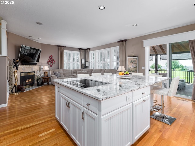 8833 SE Bristol Park Dr, Happy Valley, OR 97086 - kitchen with black electric cooktop, open floor plan, light wood finished floors, white cabinets, and recessed lighting
