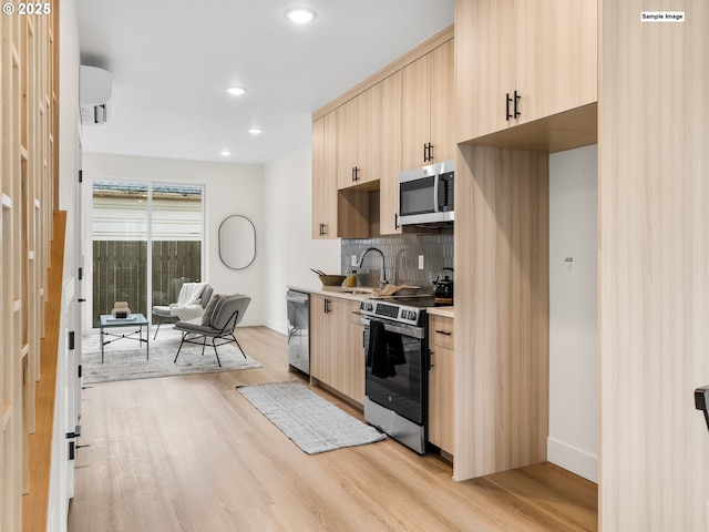 kitchen with light brown cabinets, a sink, decorative backsplash, light wood-style floors, and appliances with stainless steel finishes