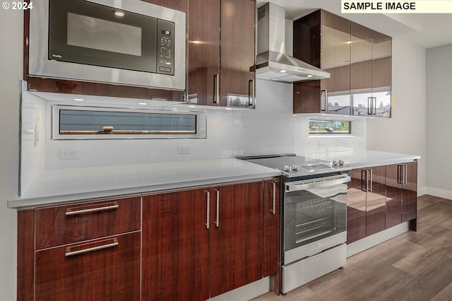 12343 SE Falling Rain Way, Happy Valley, OR 97086 - kitchen featuring wall chimney exhaust hood, stainless steel appliances, dark wood finished floors, modern cabinets, and backsplash