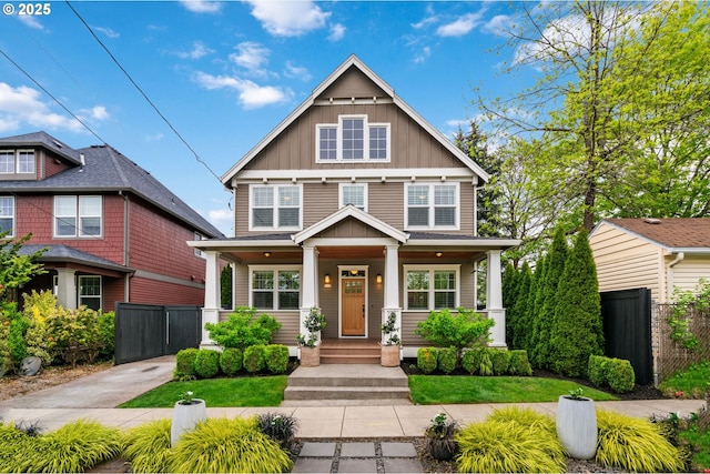 american foursquare style home featuring board and batten siding, fence, and a porch