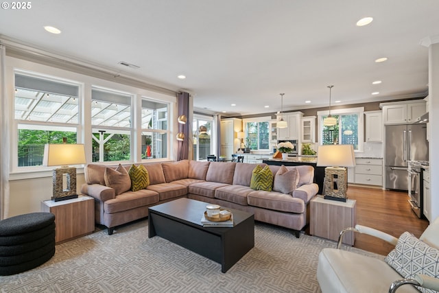 living room featuring recessed lighting, ornamental molding, and visible vents