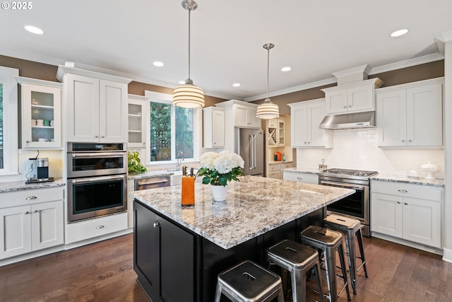 kitchen featuring crown molding, a center island, white cabinetry, under cabinet range hood, and premium appliances