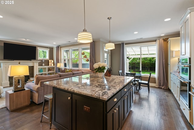 kitchen featuring crown molding, light stone countertops, a center island, white cabinetry, and dark wood finished floors