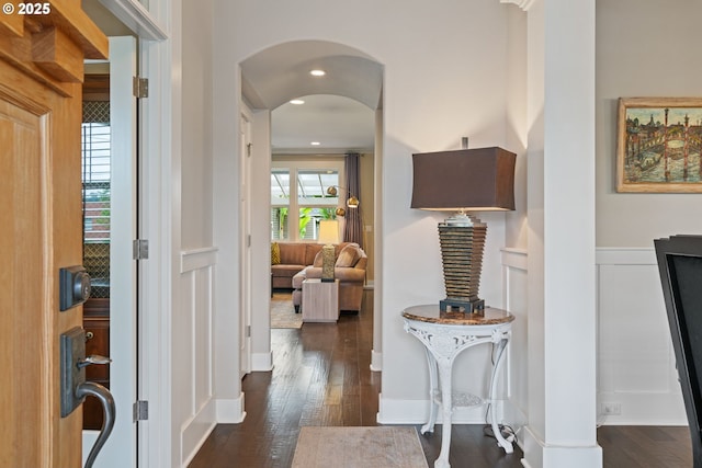 entrance foyer featuring arched walkways, dark wood finished floors, recessed lighting, and a wainscoted wall