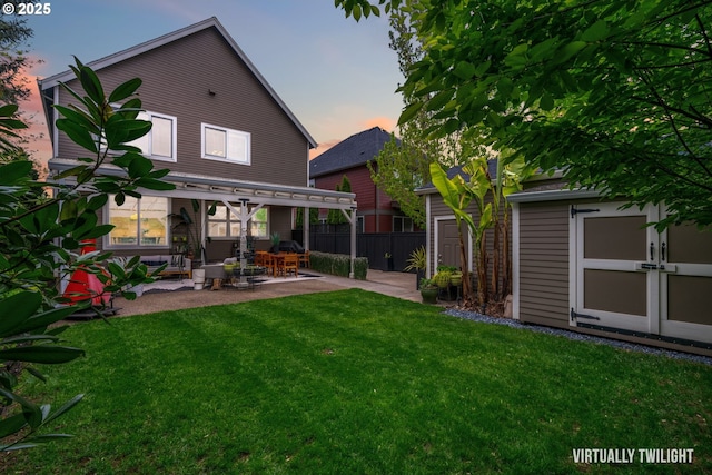 rear view of house featuring fence, an outdoor structure, a shed, a yard, and a patio
