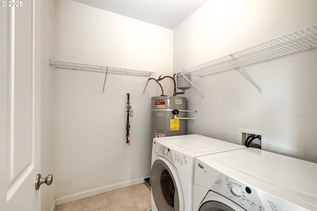 laundry area with secured water heater, washing machine and clothes dryer, and baseboards