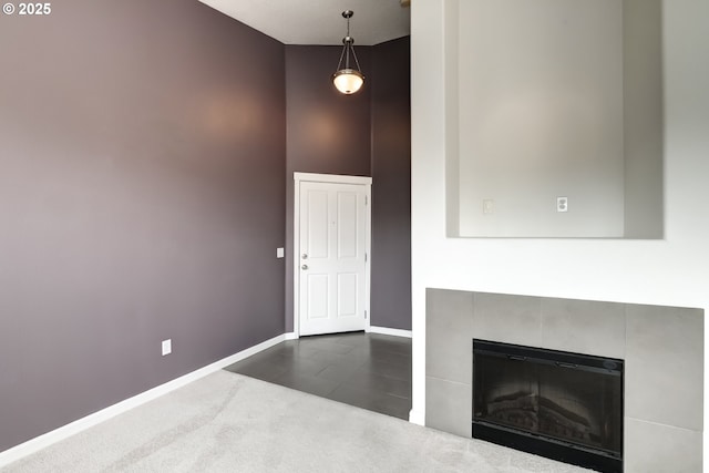 foyer entrance with a high ceiling, baseboards, a tile fireplace, and dark tile patterned floors