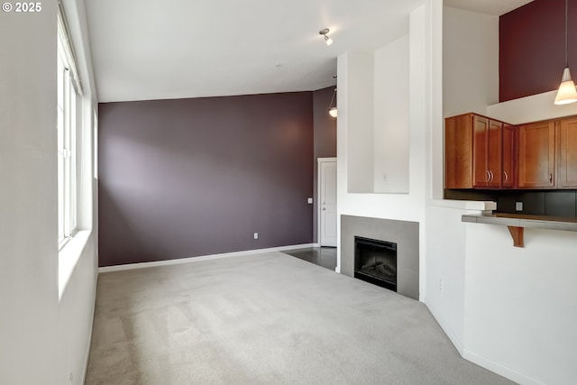 unfurnished living room with carpet floors, a fireplace, and baseboards
