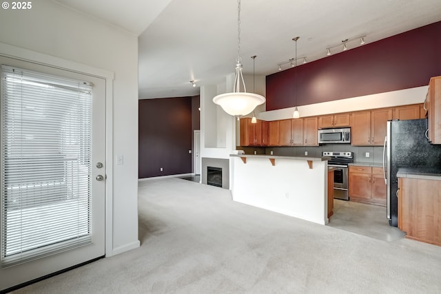 kitchen with stainless steel appliances, light carpet, a kitchen bar, open floor plan, and track lighting