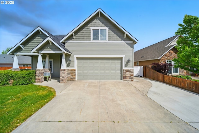 craftsman-style house with a front lawn, fence, stone siding, concrete driveway, and an attached garage