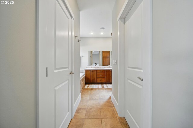 hall with light tile patterned floors, recessed lighting, and a sink