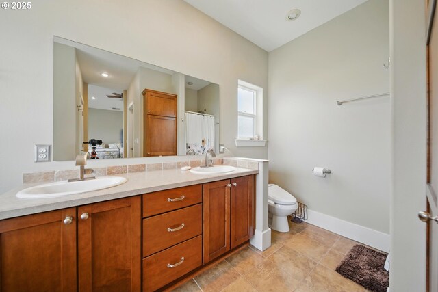 bathroom with double vanity, toilet, a sink, and ensuite bathroom
