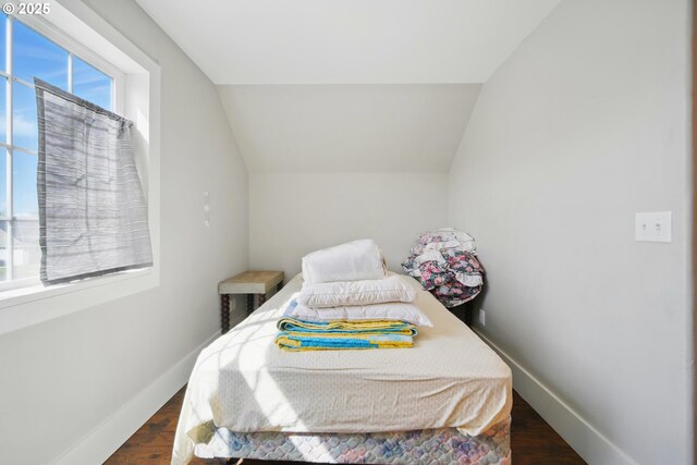 bedroom with baseboards, wood finished floors, and lofted ceiling